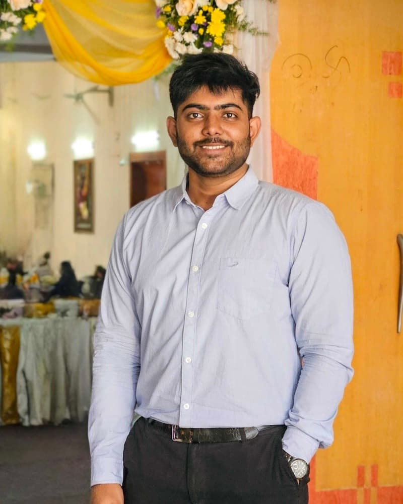 Lokesh B M smiling, standing in a light blue shirt